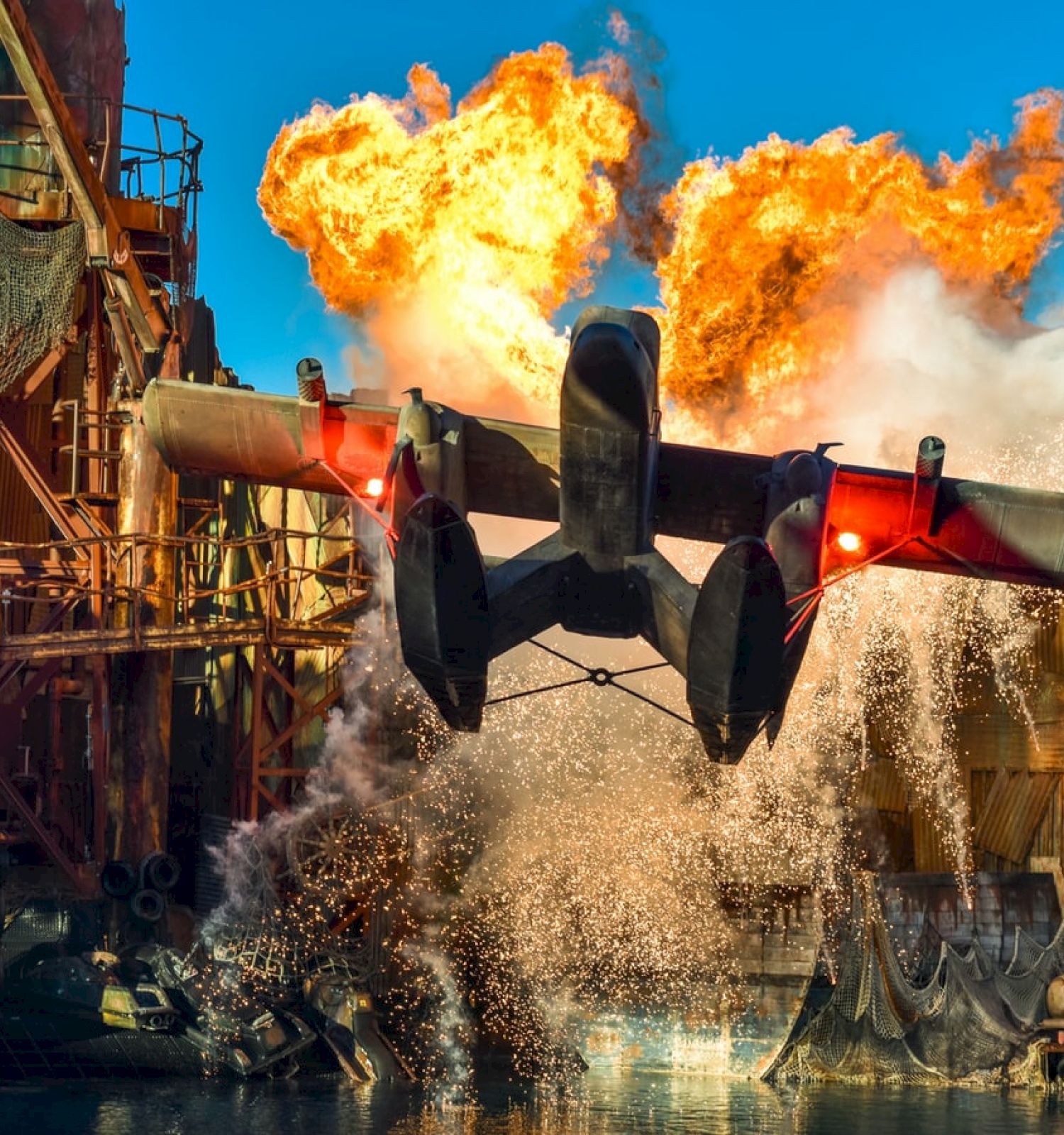 A dramatic scene featuring a flying aircraft with explosions and water splashing, set in an industrial environment.